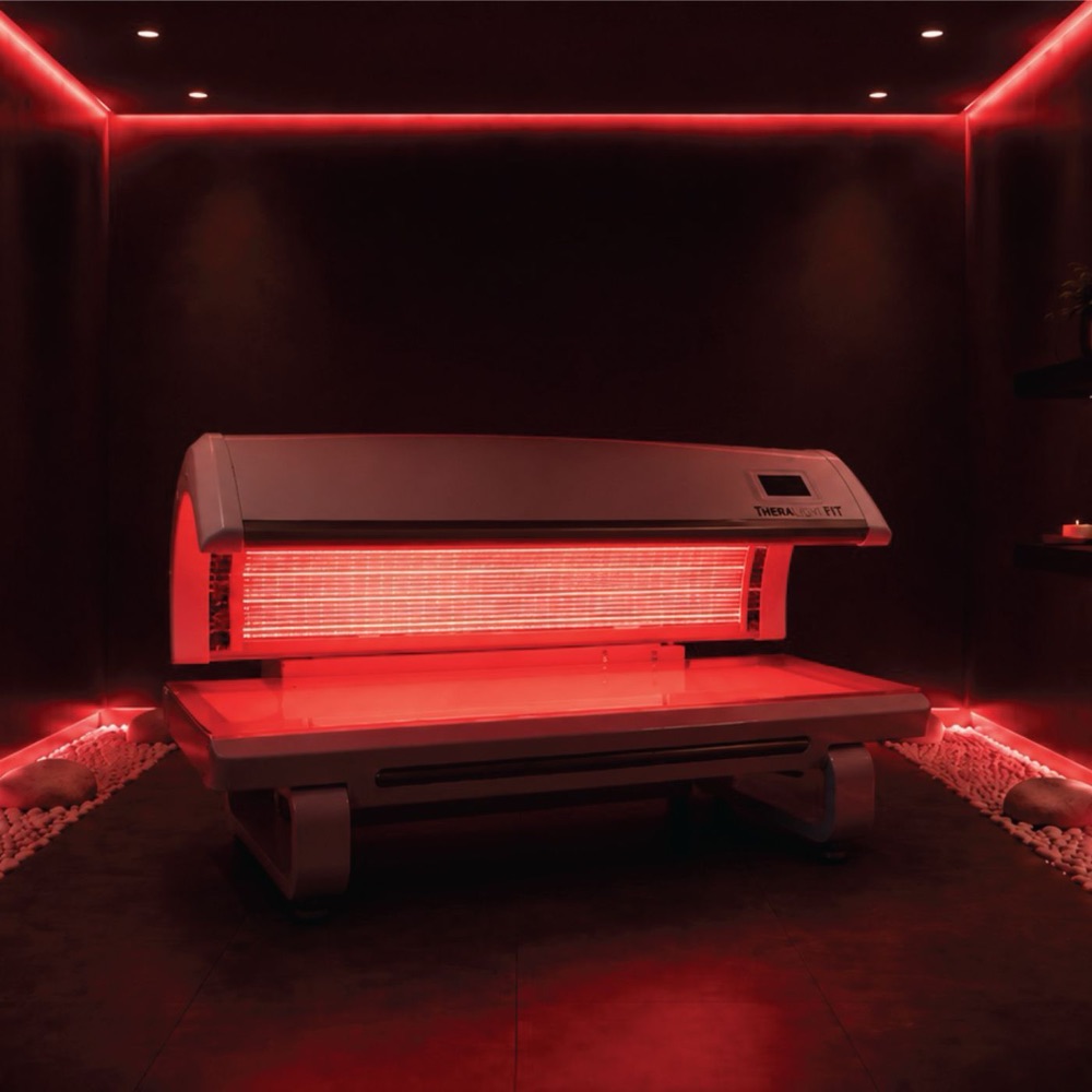The red-light therapy bed, lit in deep red